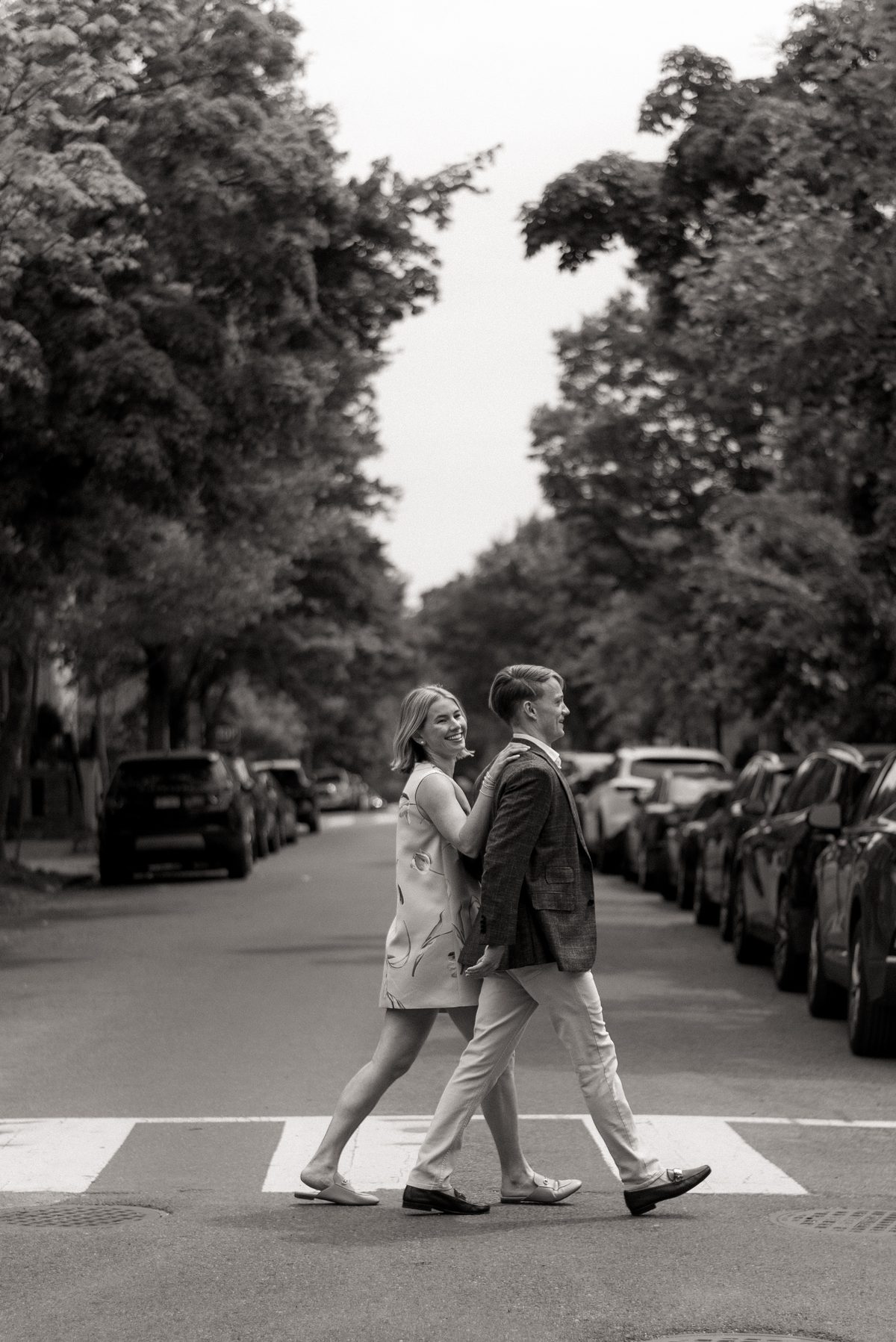 Nolan and Nikole crossing a tree-lined street, laughing